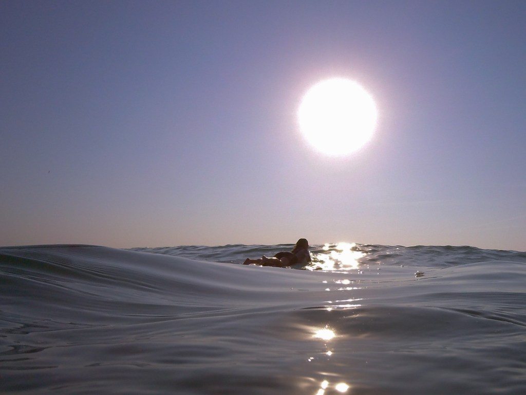 Surfer paddling out at sunrise