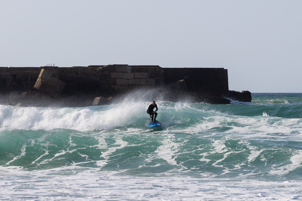 Surfer on a wave with off shore wind